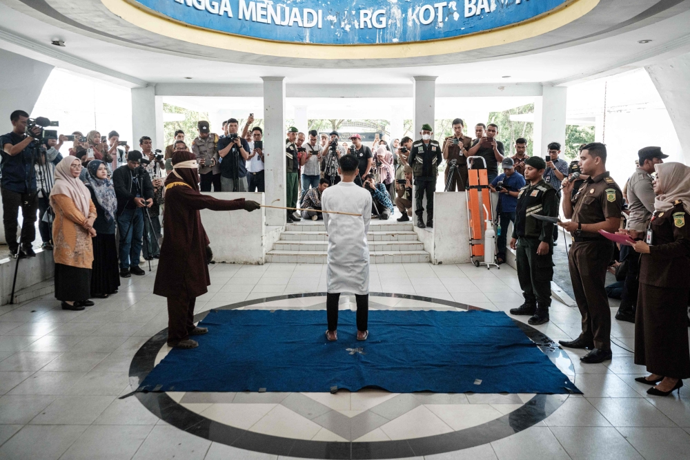A man, found guilty of sexual relations with another man under the strict Islamic sharia law, is publicly flogged in Banda Aceh, Indonesia on February 27, 2025. — AFP pic