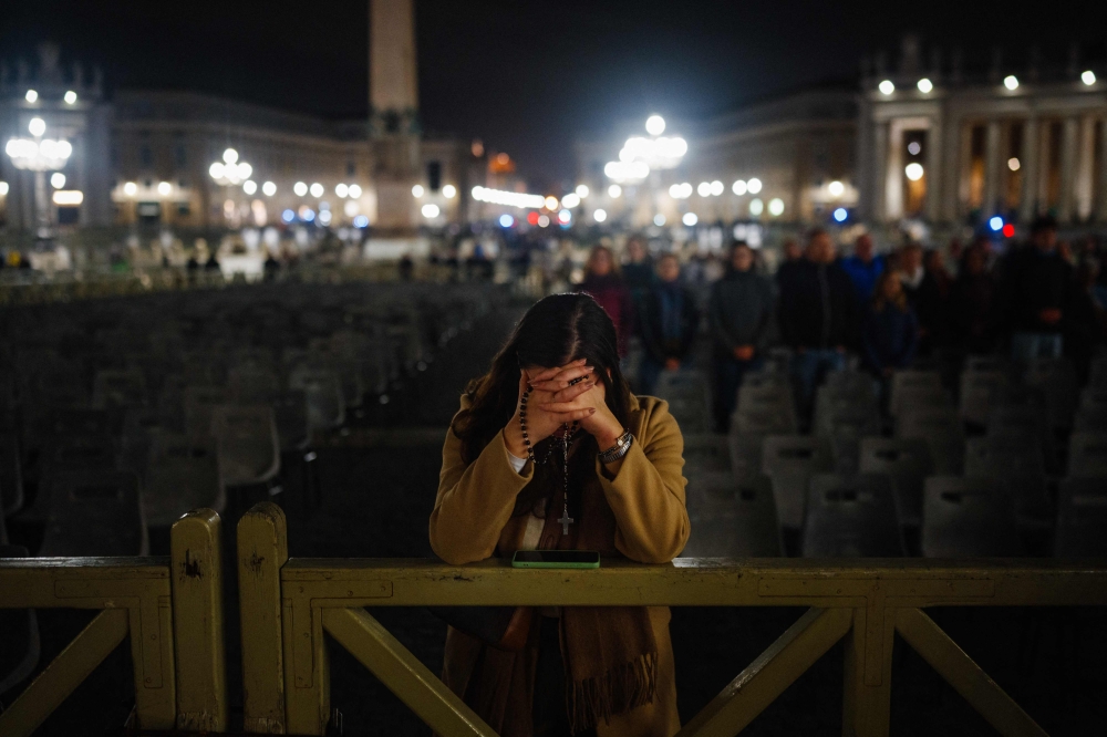 A woman prays during the rosary for the health of Pope Francis at St Peter's square in The Vatican, on February 26, 2025.— AFP pic