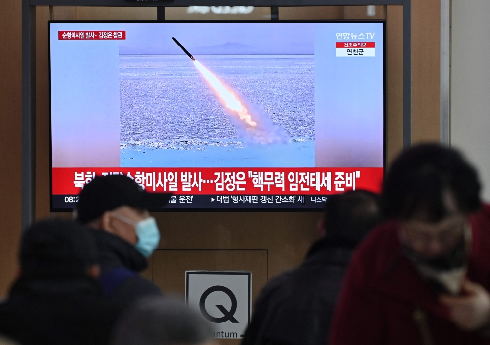 People watch a television screen showing news footage of North Korea’s latest test-launch of strategic cruise missiles, at a train station in Seoul. —  Pic by AFP