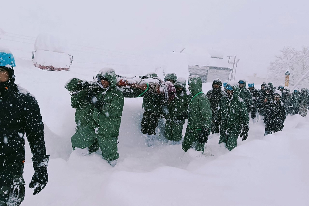 Handout photo taken and released by the State Disaster Response Force (SDRF) yesterday show  rescuers carry Border Roads Organisation (BRO) workers after an avalanche near Mana village in Chamoli district. — Pic by AFP