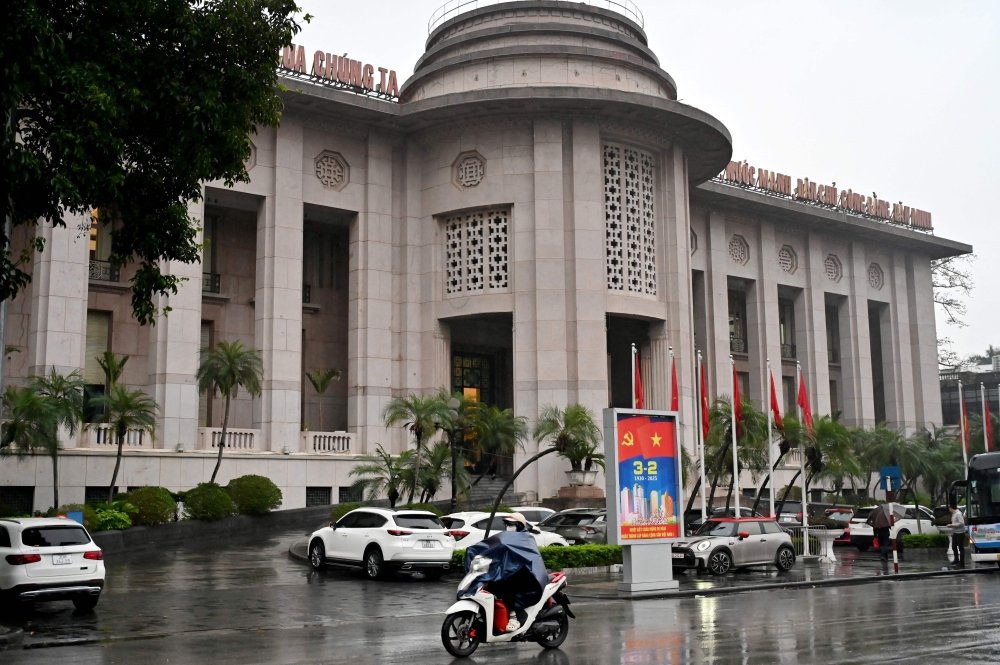 A woman rides a motorbike past the State Bank of Vietnam in Hanoi on February 25, 2025. — AFP pic