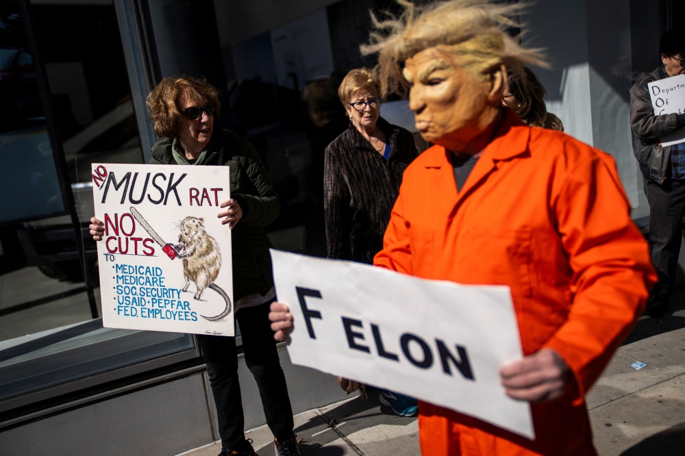 A man wearing a Donald Trump mask representing taking part in a protest outside of a Tesla store during a National Day of Tesla Protest in New York City. – Pic by Reuters