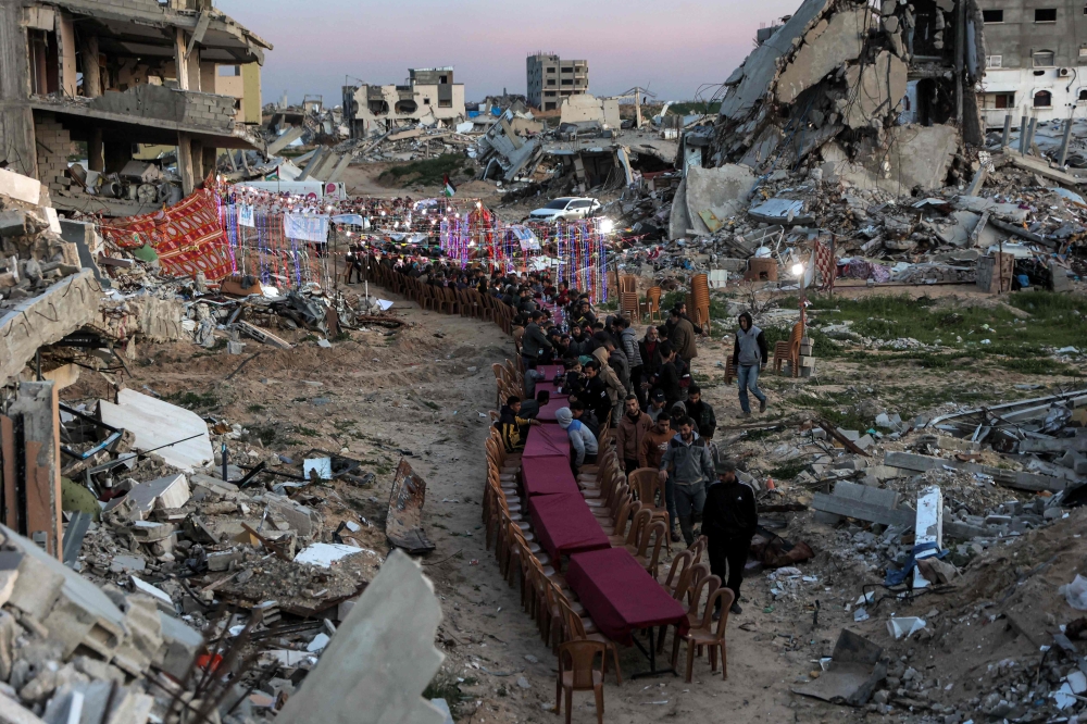People gather by the rubble of destroyed buildings for a mass gathering for a communal iftar fast-breaking meal on the second day of the Muslim holy month of Ramadan in the area of al-Dahduh in Gaza City's Tal al-Hawa district on March 2, 2025 amid the ongoing truce in the war between Israel and Hamas. — AFP pic