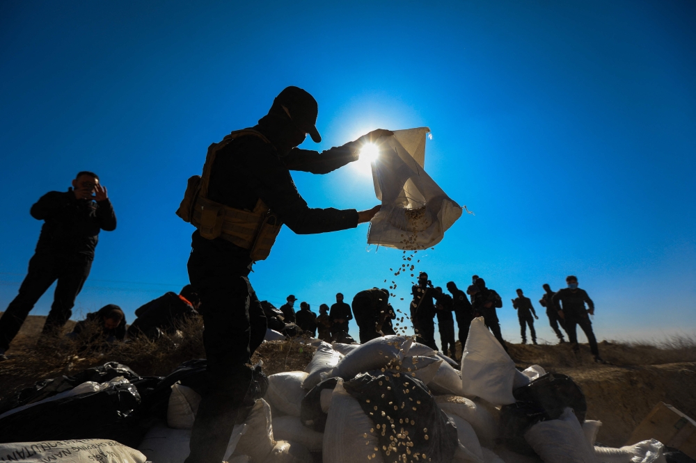 A member of the security forces of Syria’s new authorities empties a sack of Captagon into a ditch to burn them in a field near the Fourth Division’s Security Bureau on the outskirts of Damascus on January 19, 2025. — AFP pic
