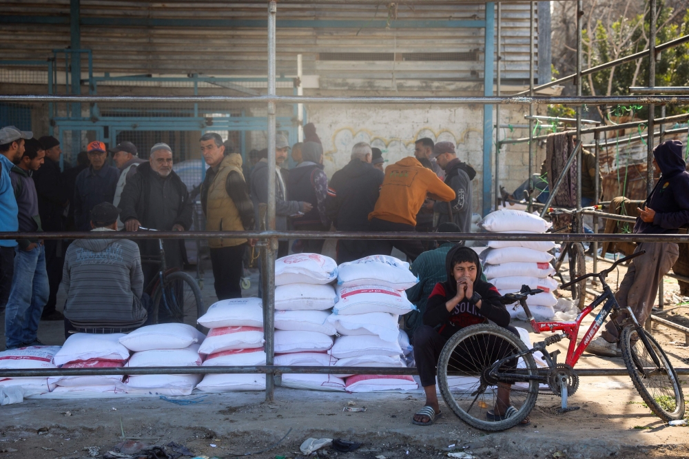 Palestinians queue to receive food aid from an UNRWA distribution center at the Nuseirat refugee camp in the central Gaza Strip on March 3, 2025. — AFP pic