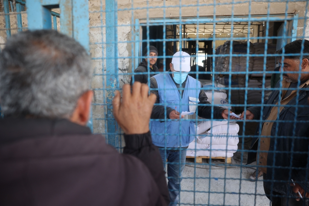 Palestinians queue to receive food aid from an UNRWA distribution center at the Nuseirat refugee camp in the central Gaza Strip on March 3, 2025. — AFP pic