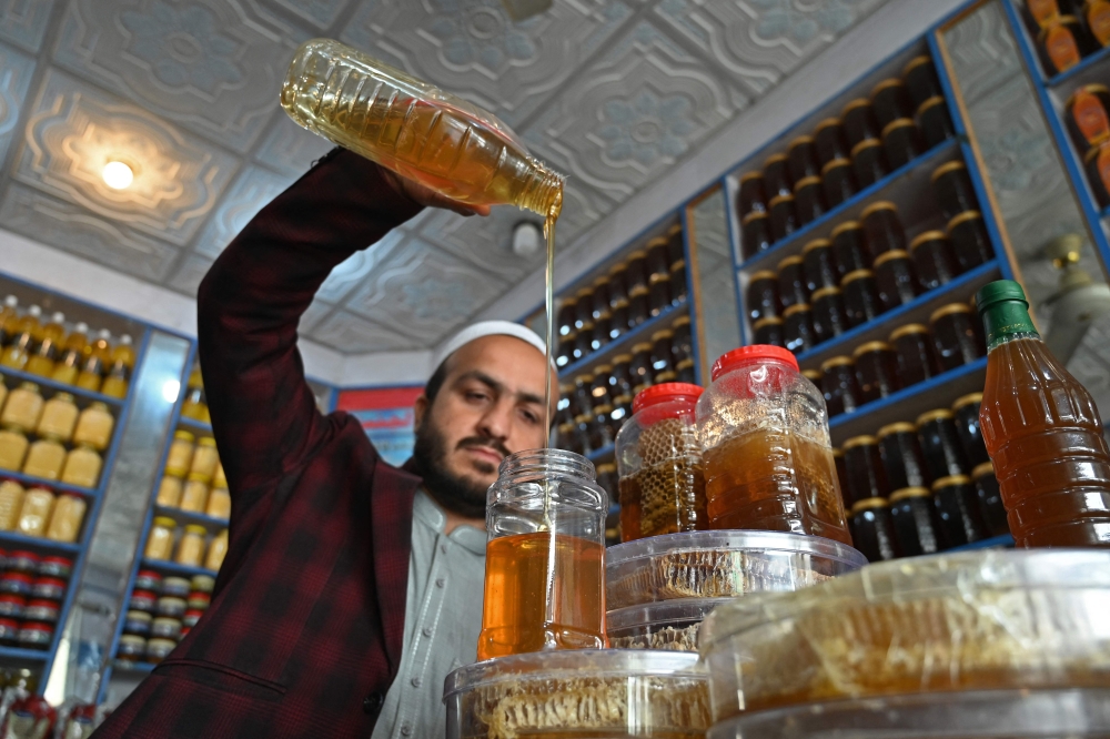 A seller fills a bottle with honey at his shop in Chamkanni on the outskirts of Peshawar in Khyber Pakhtunkhwa province, Pakistan. — AFP pic