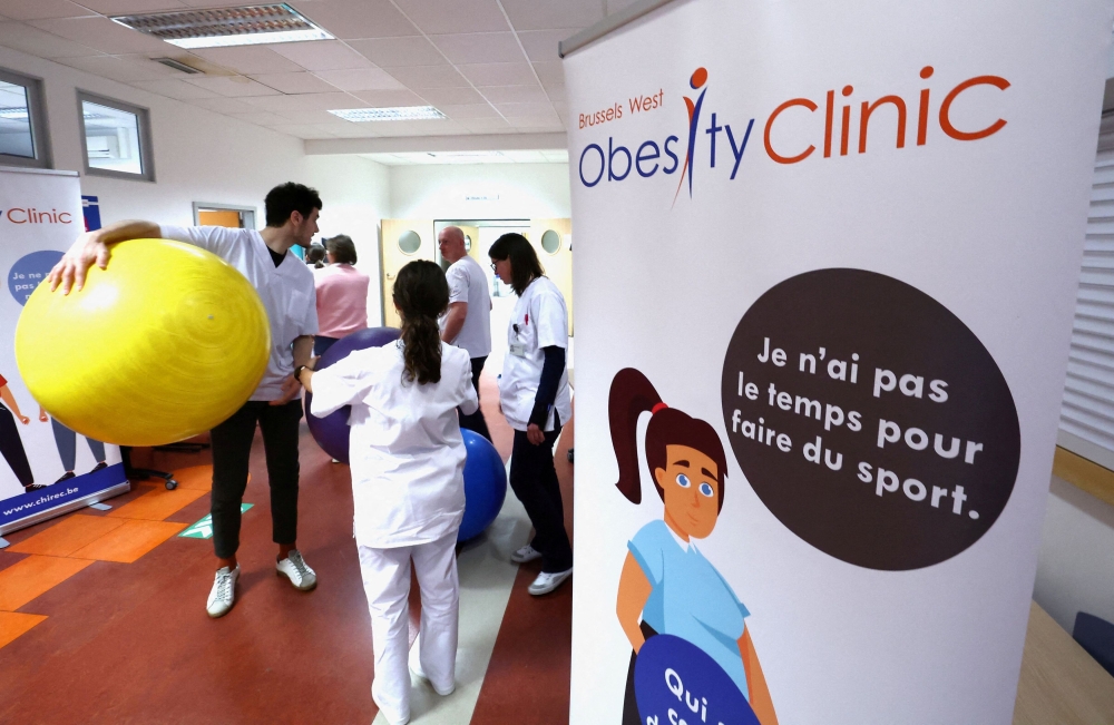 Nurses and doctors stand next to a banner advertising the Brussels West Obesity Clinic during a 2-day event marking World Obesity Day in March 2024. — AFP pic