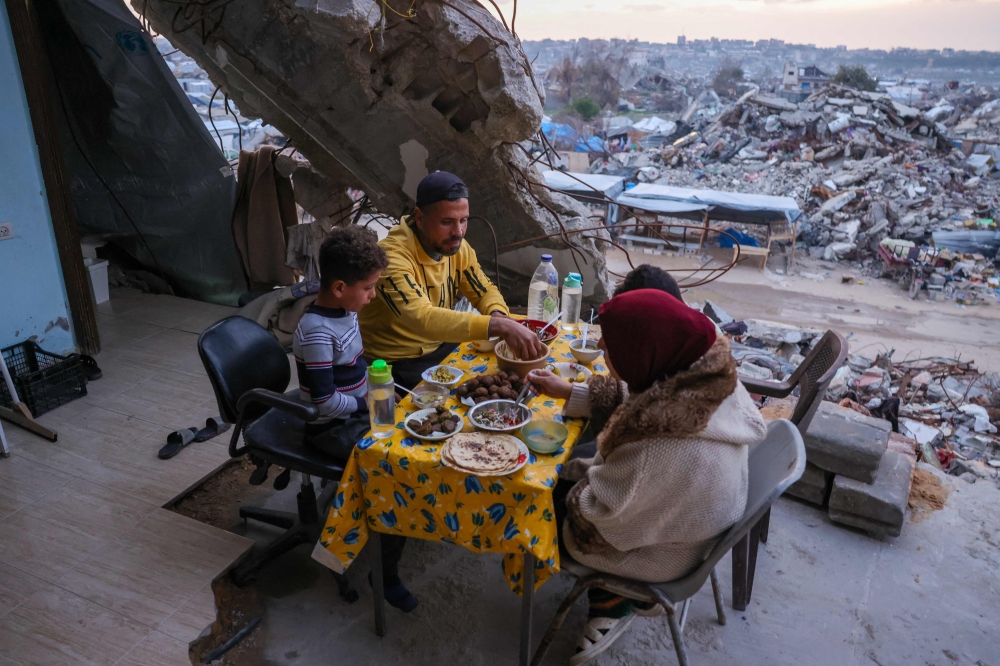 A Palestinian family breaking fast in their destroyed house amid the rubble of buildings in Beit Lahia in the northern Gaza Strip on March 4, 2025, during the Muslim holy fasting month of Ramadan. — AFP pic