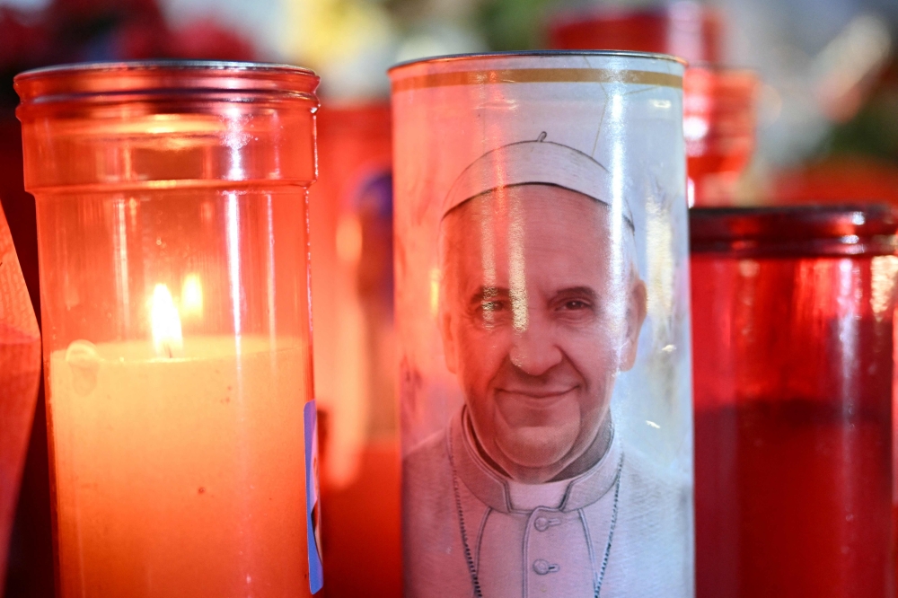 Candles are lit at the statue of John Paul II outside the Gemelli University Hospital where Pope Francis is hospitalized with pneumonia, in Rome. — AFP pic