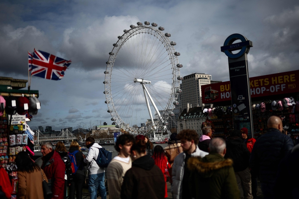 Pedestrians walk along Embankment backdropped by The London Eye, in London, on February 25, 2025. Floating high above the London skyline aboard her most famous creation, architect Julia Barfield said she never expected the London Eye to take off as a design icon. — AFP pic