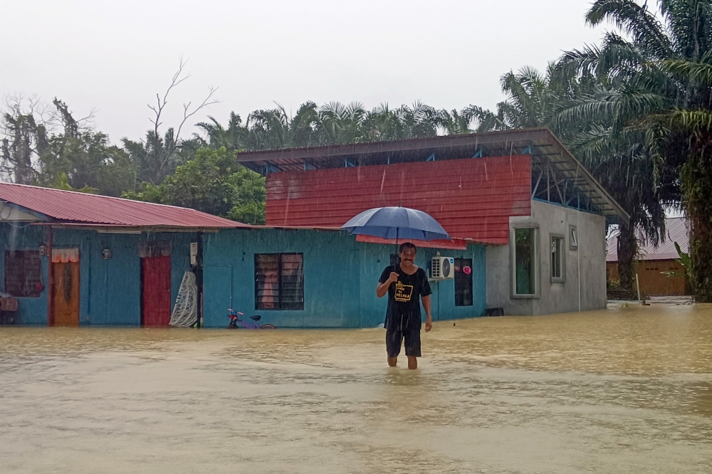 A resident wades through floodwater at Kampung Kilang Berapi in Merlimau, March 6, 2025. The floods were triggered by continuous heavy rain lasting more than an hour from 11pm on Wednesday. — Bernama pic 
