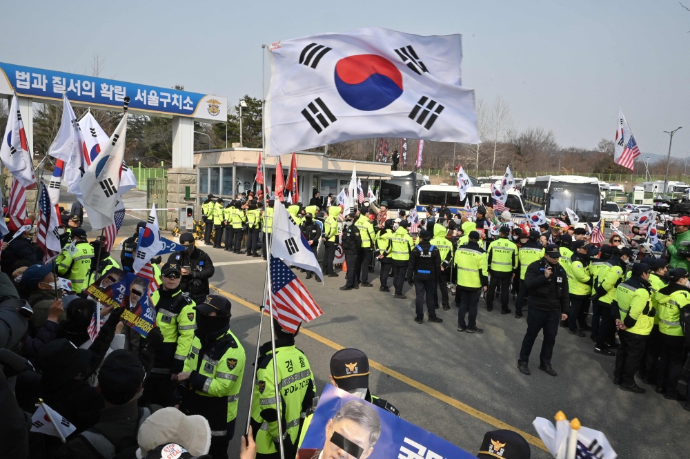 Supporters of arrested and impeached South Korean President Yoon Suk Yeol wave the national flags as they gather outside the Seoul Detention Center in Uiwang. — AFP pic