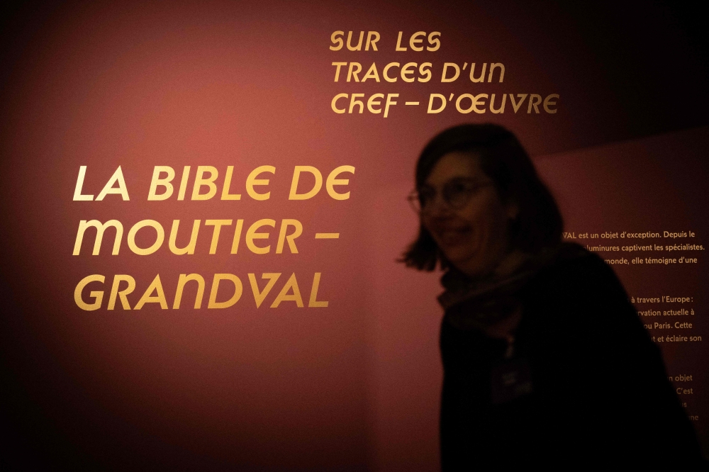 A woman walks past the sign announcing the view of the exhibition ‘Sur les traces d’n chef-d’euvre: La Bible de Moutier-Granval’ or ‘On the trail of a masterpiece’ at the Mus’ jurassien d’rt et d’istoire (MJAH), in Delemont, the capital of the Swiss canton of Jura on February 6, 2025. — AFP pic