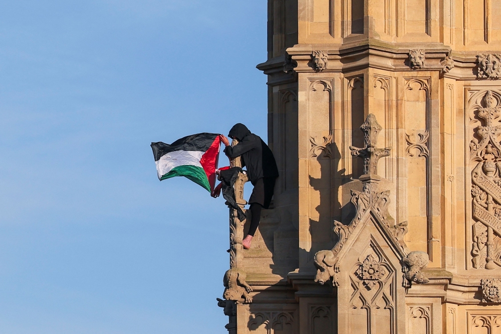 A man with a Palestinian flag sits on the Elizabeth Tower, commonly known as Big Ben, next to Houses of Parliament, in London, Britain March 8, 2025. — Reuters pic 