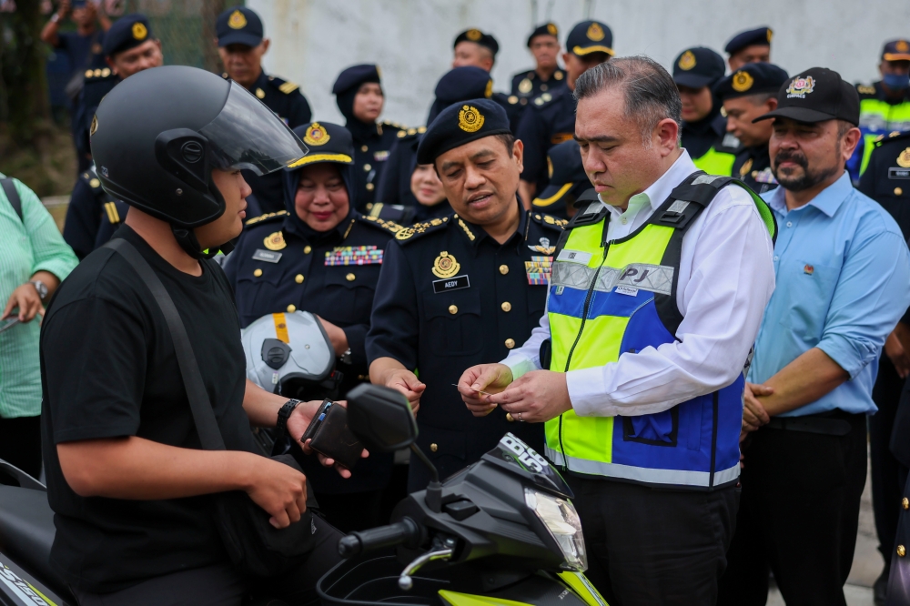 Transport Minister Anthony Loke inspects a motorcycle rider’s driving licence during a special operation at the Road Transport Department's Enforcement Station in Semenyih yesterday.  — Bernama pic