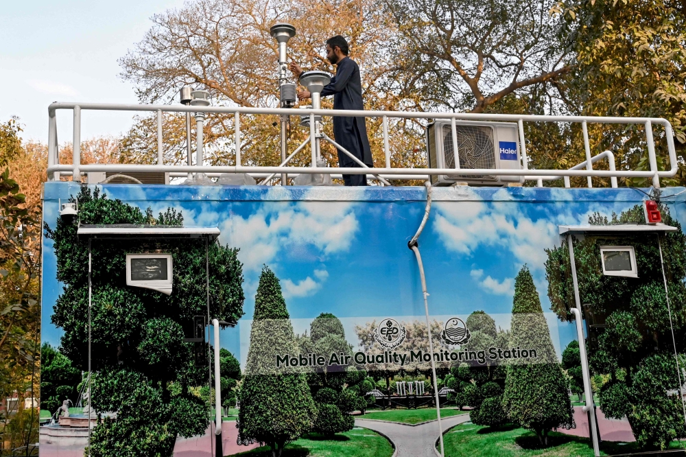 This photograph taken on February 17, 2025 shows an Anti-Smog Squad (ASS) technician inspecting a mobile air quality monitoring station in Lahore. Tens of millions of Pakistanis spent at least four months breathing toxic air pollution 20 times above safe levels, in the worst winter smog season for several years, according to data analysed by AFP. — AFP pic 