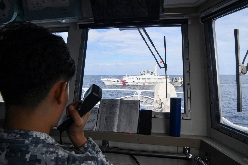 This file photo taken on August 22, 2023 shows a female member of the Philippine Coast Guard's all-women 'Angels of the Sea' programme issuing a radio challenge to a Chinese coast guard ship. — AFP pic
