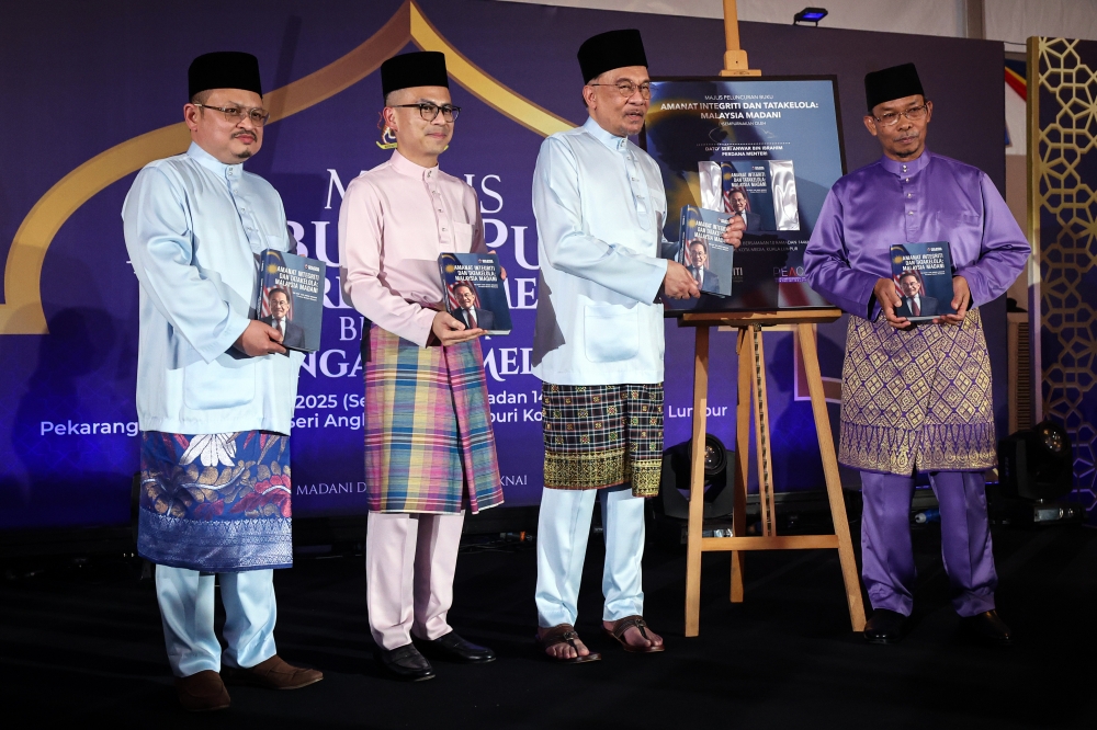 Prime Minister Datuk Seri Anwar Ibrahim holds a copy of ‘Mandate for Integrity and Governance: Malaysia MADANI’ during the book’s launch in Kuala Lumpur March 11, 2025. — Bernama pic