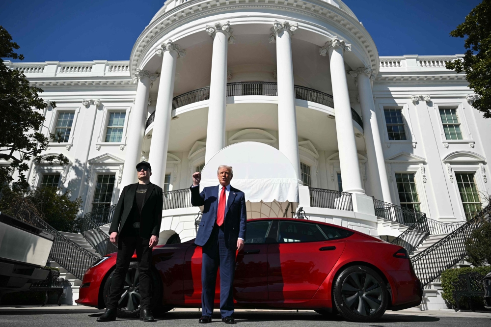 US President Donald Trump and Tesla CEO Elon Musk speak to the press as they stand next to a Tesla vehicle on the South Portico of the White House on March 11, 2025 in Washington, DC. — AFP pic