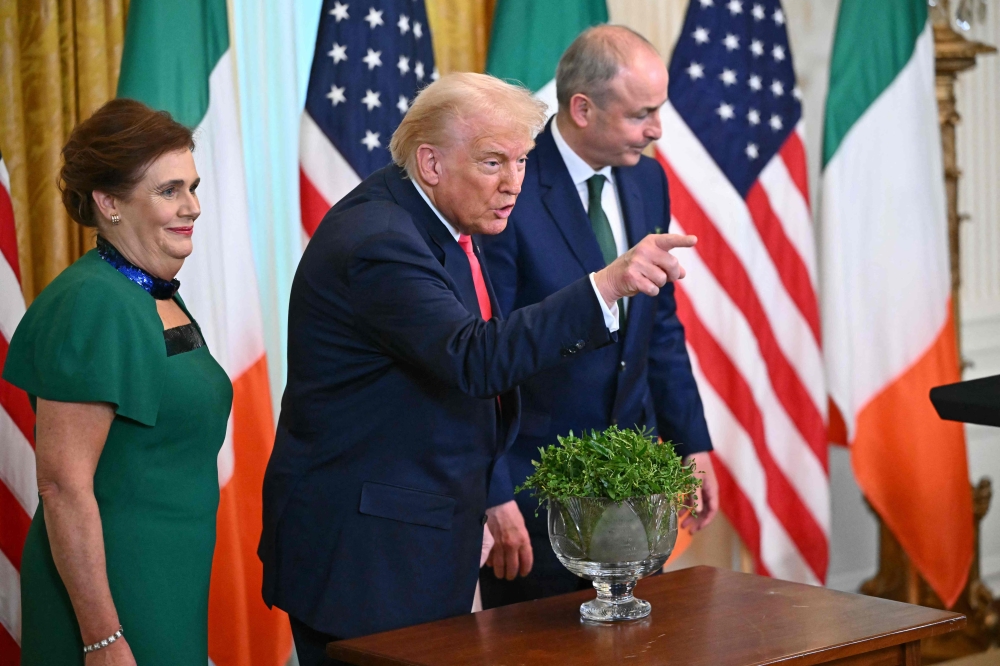 US President Donald Trump gestures alongside Irish Prime Minister Micheal Martin (R) and his wife Mary O'Shea (L) during a St. Patrick's Day Reception in the East Room of the White House in Washington yesterday. — AFP pic