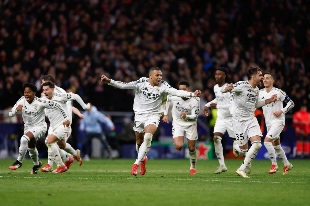 Real Madrid’s French forward #09 Kylian Mbappe (C) celebrates with teammates after their penalty shootout victory over Atletico Madrid in the UEFA Champions League Round of 16 second-leg match at the Metropolitano Stadium in Madrid. — AFP
