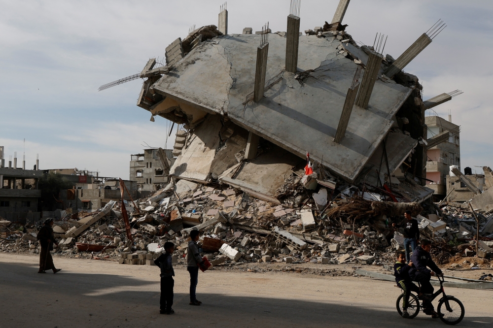Palestinians pass by a rubble of houses destroyed during the Israeli offensive, in Rafah, in the southern Gaza Strip, March 13, 2025. — Reuters pic 