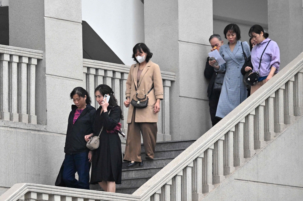 Relatives of victims of a 2023 apartment block fire walk out from the Hanoi People’s Court after a sentencing in the case in Hanoi on March 14, 2025. — AFP pic 