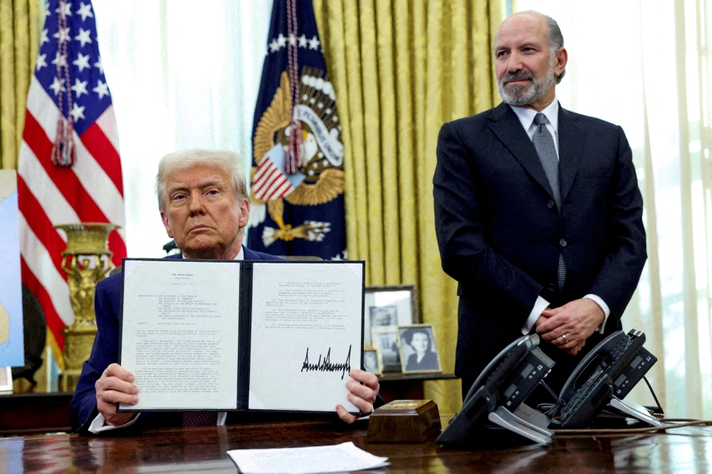 File picture of US President Donald Trump holding an executive order about tariffs increase, flanked by US Commerce Secretary Howard Lutnick, in the Oval Office of the White House in Washington, DC, US February 13, 2025. —  Reuters pic