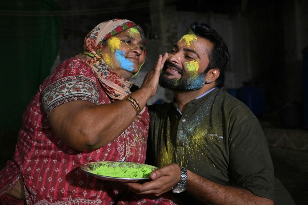 A mother paints the face of her son as they celebrate Hindu festival of Holi in Tharparkar district of the desert town of Mithi, south-eastern Pakistan, March 13, 2025. — AFP pic