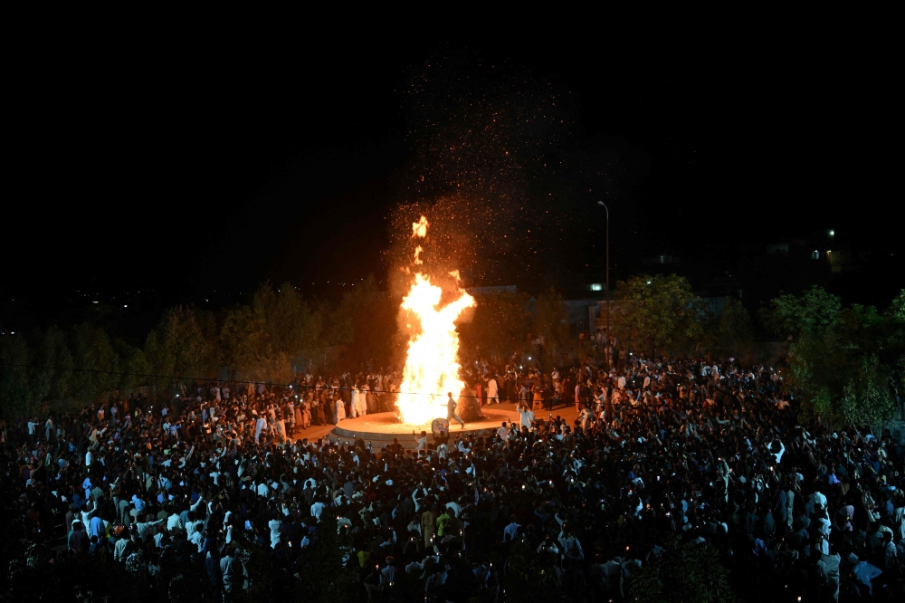 People gather around a bonfire as they celebrate Hindu festival of Holi in Tharparkar district of the desert town of Mithi, south-eastern Pakistan, March 13, 2025. — AFP pic