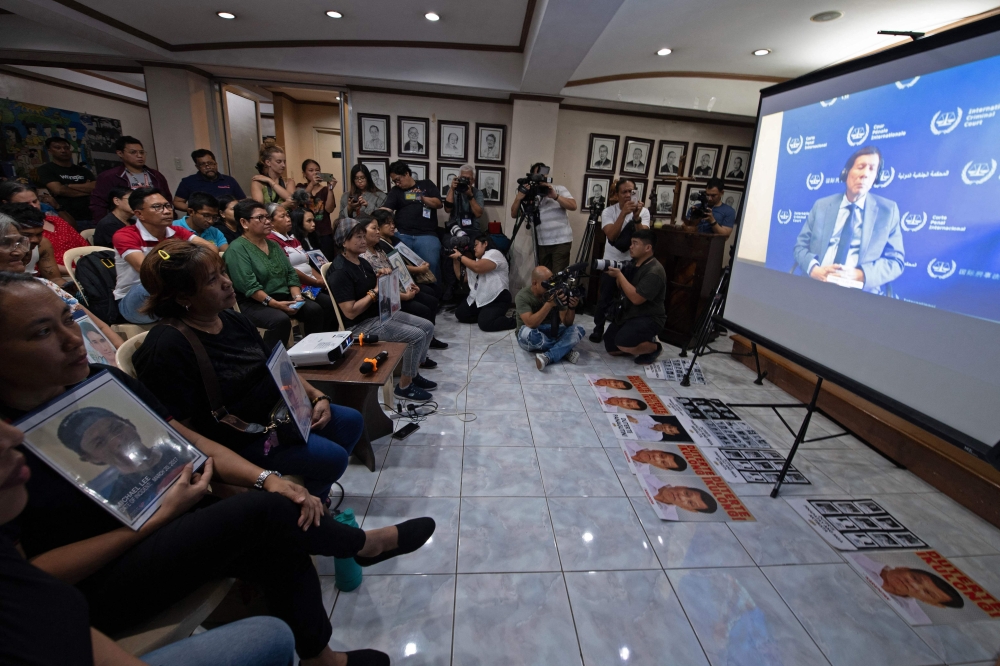 Families (holding portraits) of victims of former Philippines president Rodrigo Duterte's drug war, watch a live stream of Duterte's first appearance at the International Criminal Court (ICC) since his arrest on March 11, during a live viewing at a church building in Manila on March 14, 2025. — AFP pic