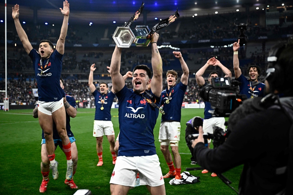 France's scrum-half Nolann Le Garrec holds the trophy while France's players celebrate winning the Six Nations international rugby union tournament at the end of their match against Scotland yesterday. — AFP pic