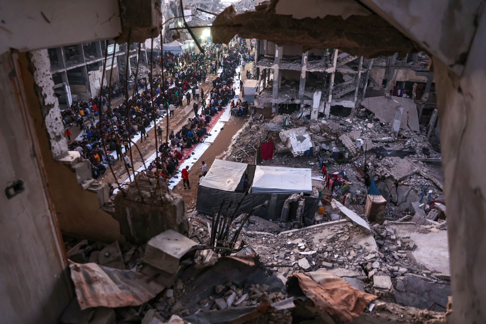 Palestinians gather for a mass fast-breaking iftar meal amid the rubble of destroyed buildings in Beit Lahia in the northern Gaza Strip yesterday. — AFP pic