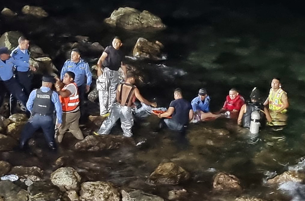 Handout picture released by Honduran Police shows rescue teams carrying an injured man out of the water after a plane crash in Roatan, Honduras yesterday. — AFP pic