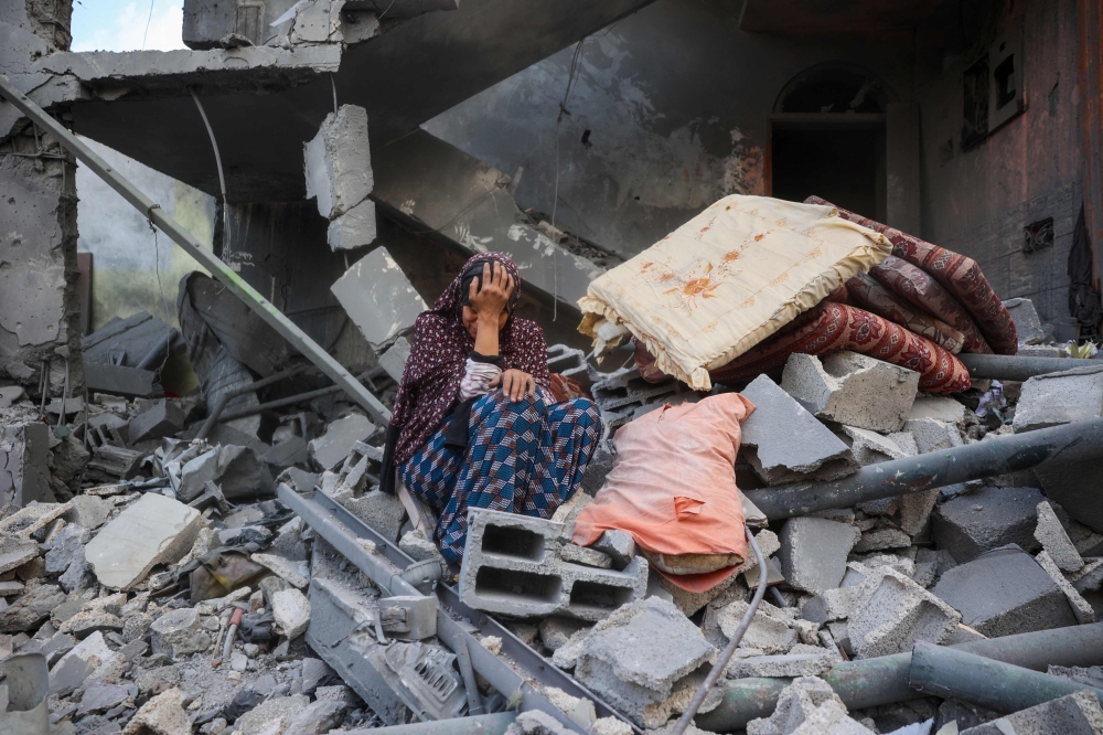 A woman cries while sitting on the rubble of her house, destroyed in an Israeli strike, in the Nuseirat refugee camp in central Gaza Strip on March 18, 2025. — AFP pic