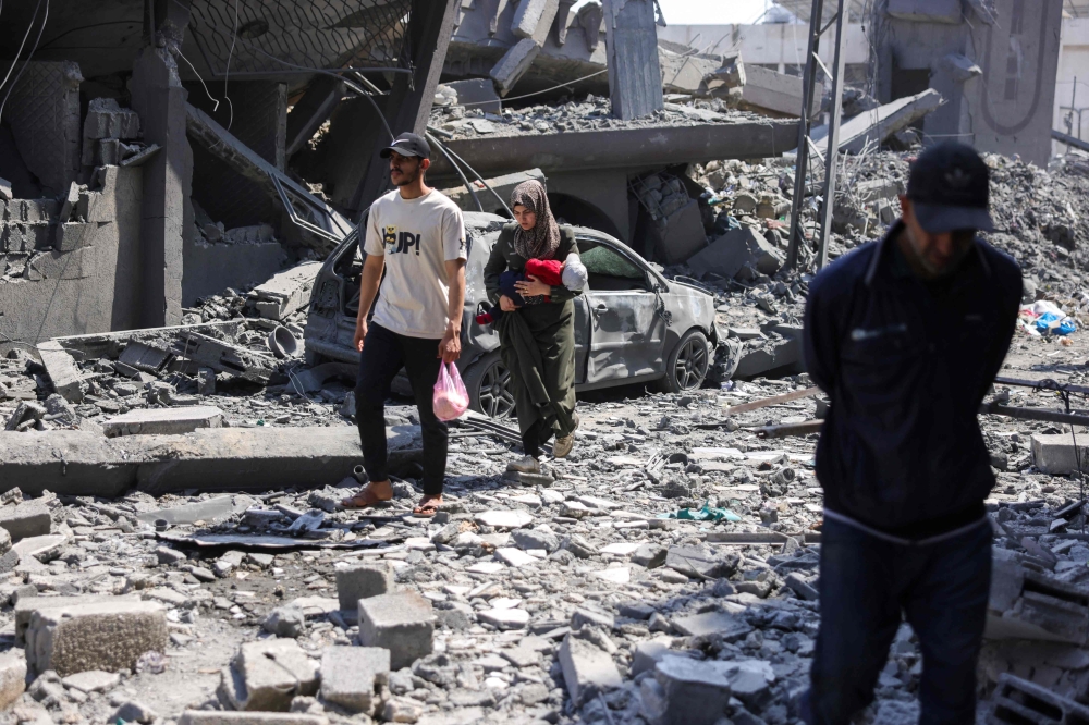 Residents walk amid the rubble of a building destroyed in an overnight Israeli strike in Jabalia, in the northern Gaza Strip yesterday. — AFP pic