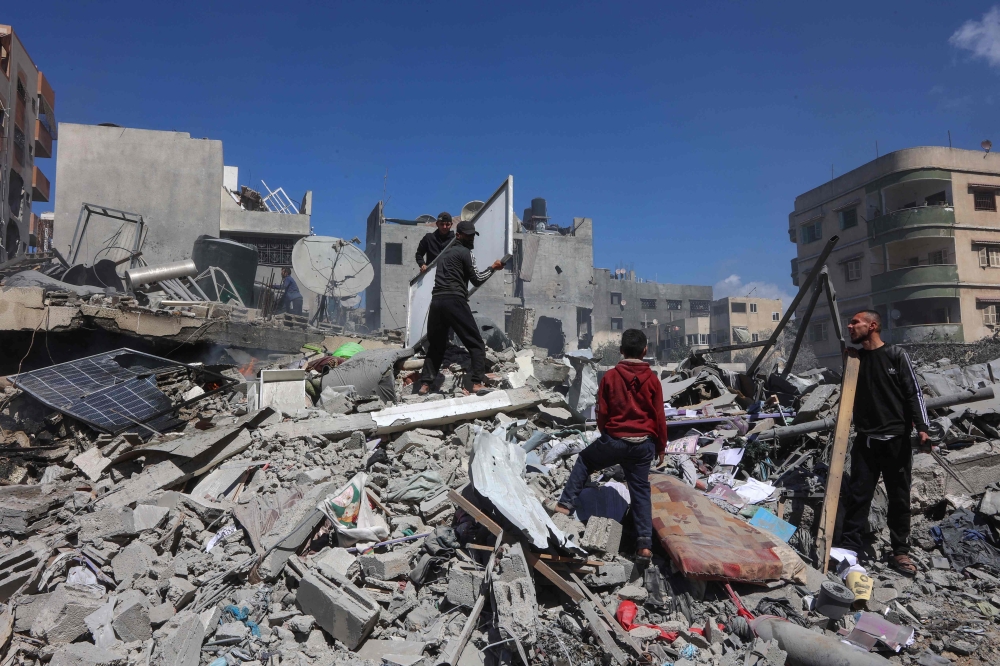Palestinians inspect the rubble of the Elias Tarazi family house after it was destroyed in an Israeli strike in al-Sabra neighbourhood in Gaza City yesterday. — AFP pic