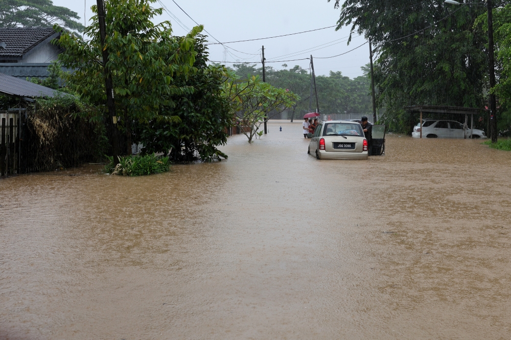A Kampung Kangkar Tebrau resident moves his car following floods during Bernama’s survey in Johor Baru today. — Bernama pic