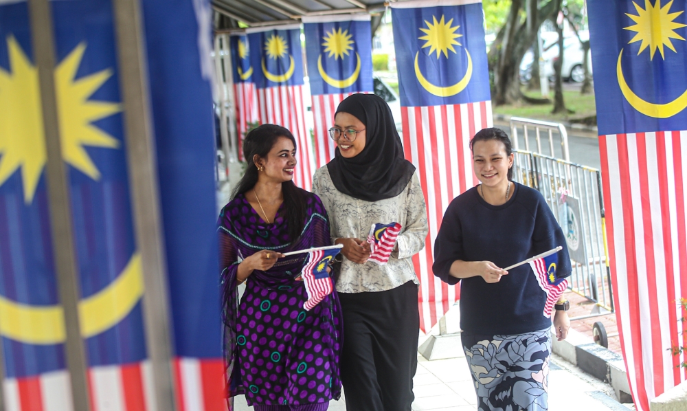 People walk near Jalur Gemilang decorations in Ipoh on Aug 21, 2023. — Picture by Farhan Najib