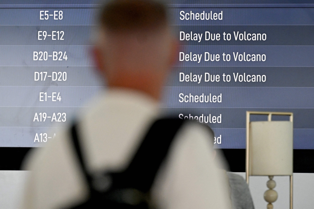 Passengers look at an electronic board displaying cancelled flights at the Ngurah Rai International Airport in Tuban near Denpasar on Indonesia’s resort island of Bali on March 21, 2025, after Mount Lewotobi Laki-Laki volcano in the archipelago nation’s east erupted, shooting dark ash 8km into the sky. — AFP pic
