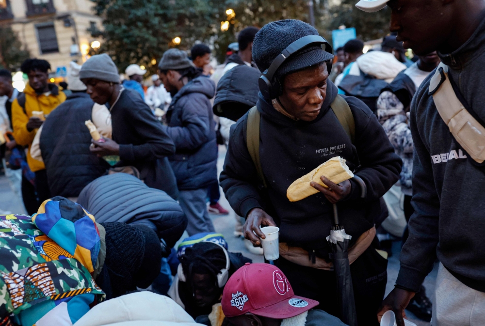 Immigrant people receive an iftar meal during the food distribution organized by a group of Senegalese people during Ramadan in Lavapies Square in Madrid, on March 19, 2025. — AFP pic