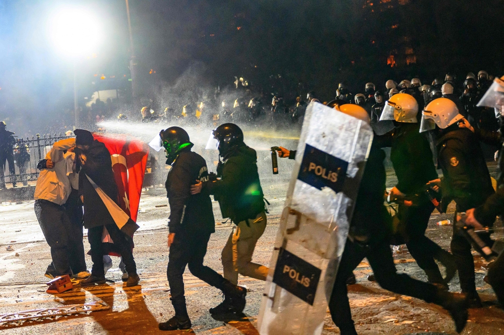 Protesters react to tear gas sprays as they clash with riot police during a demonstration following the arrest of Istanbul’s mayor, near the city hall of Istanbul, on March 21, 2025. — AFP pic