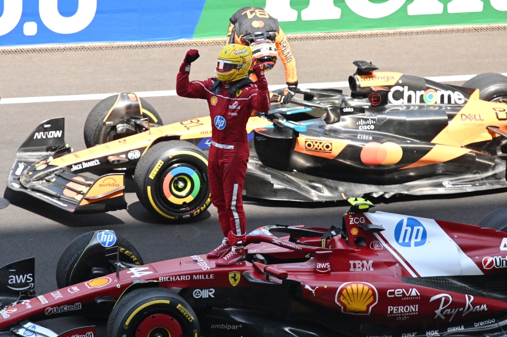 Ferrari’s Lewis Hamilton (centre) celebrates after winning the sprint race while McLaren’s Oscar Piastri (background) leaves his car after coming in second in the sprint race of the Formula One Chinese Grand Prix in Shanghai March 22, 2025. — AFP pic