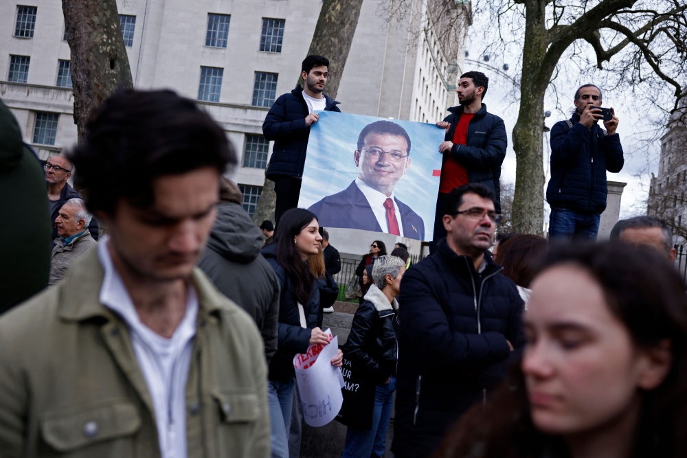 Demonstrators hold placards bearing the face of Istanbul’s arrested mayor Ekrem Imamoglu, in central London on March 22, 2025. — AFP pic