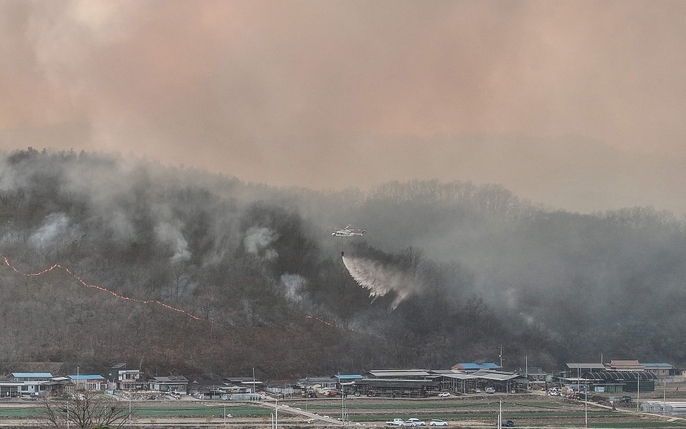 A helicopter tries to extinguish a fire after a wildfire broke out in the southeastern county of Uiseong on March 22, 2025. — Yonhap/AFP pic