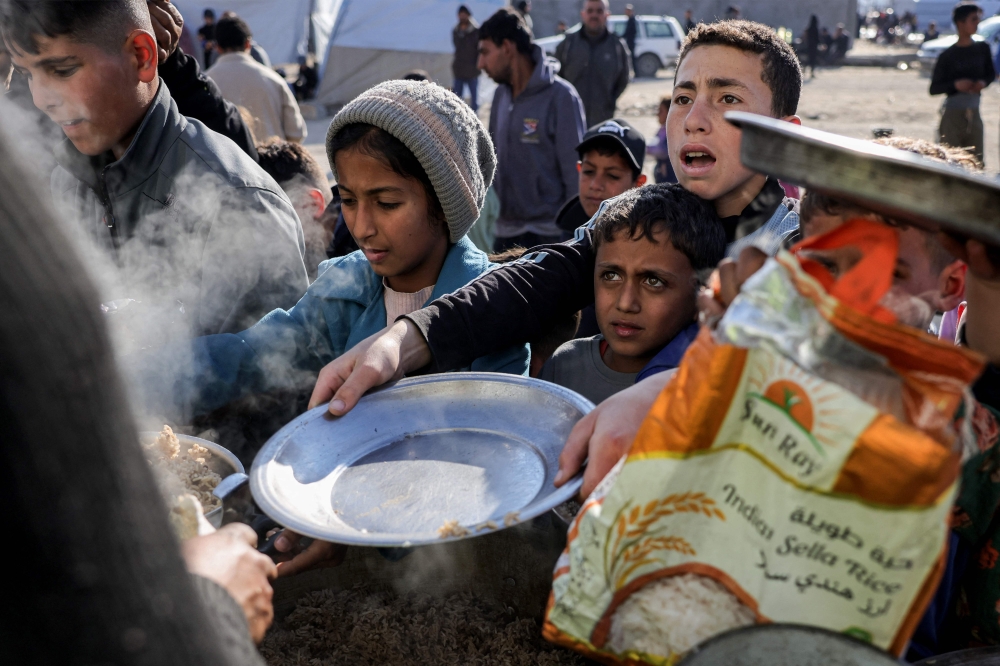 Children hold out empty pots as they queue for charity meals handed out from a kitchen during the Muslim holy fasting month of Ramadan, in Gaza City on March 22, 2025. — AFP pic