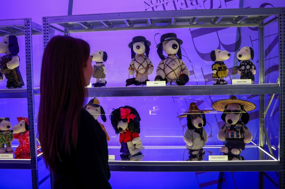 A woman looks at Snoopy figurines displayed as part of the 'Snoopy In Style' exhibition to mark the Peanuts comic strip's 75th anniversary in Paris, France, March 20, 2025. — Reuters pic