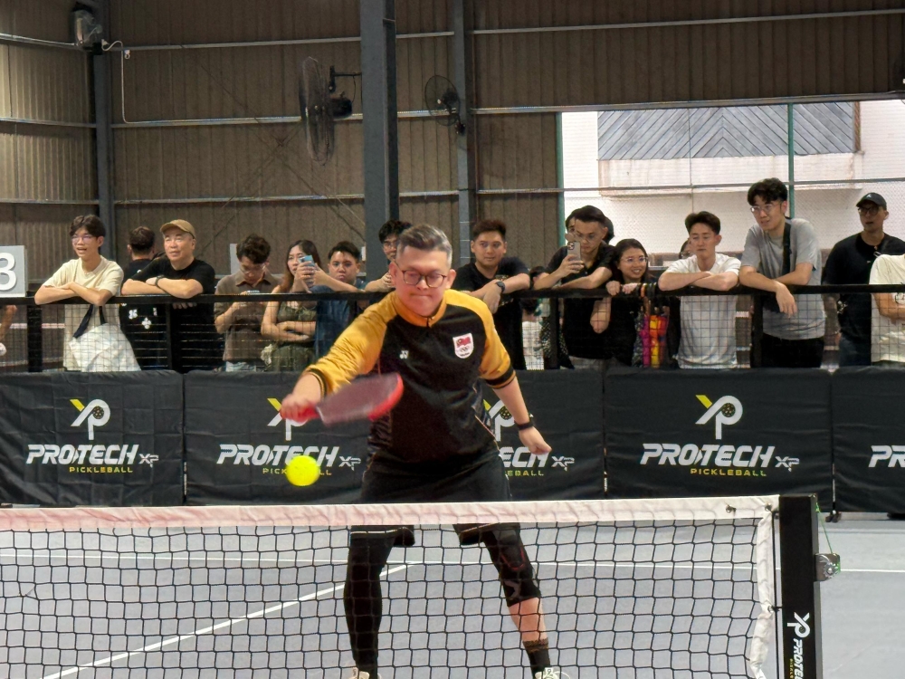Dr Yii tests out his pickleball playing skills as spectators look on yesterday. — The Borneo Post pic
