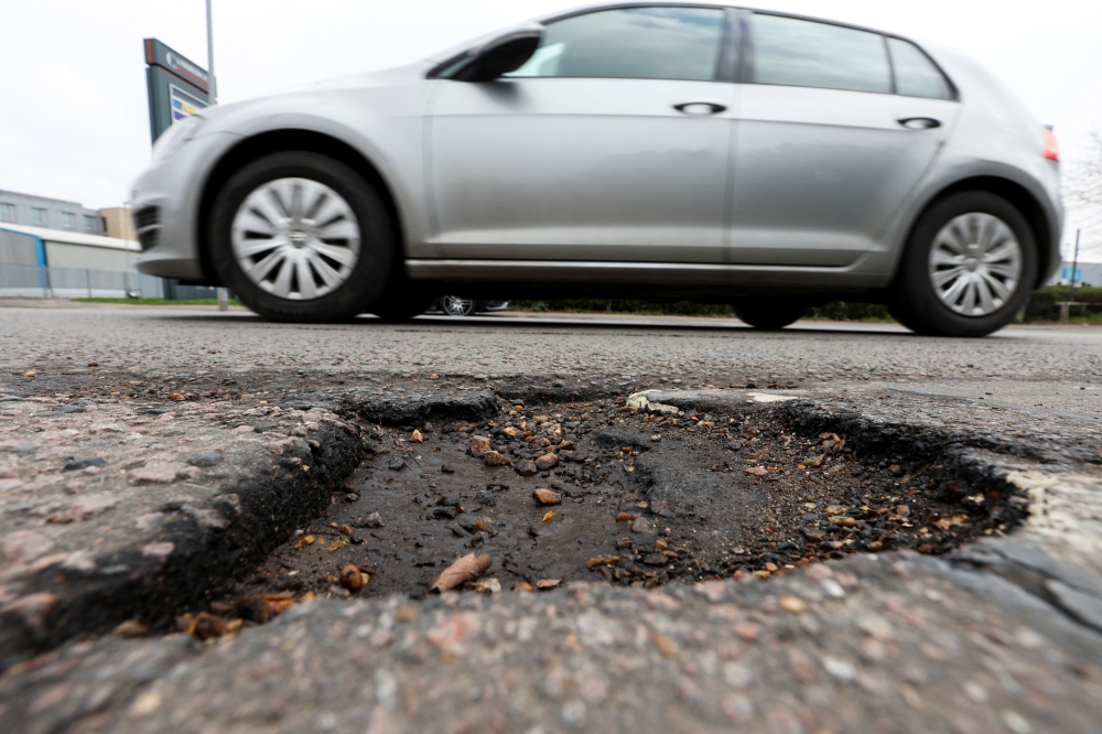A car drives past a pothole in Coldhams Lane in Cambridge, following the British government's announcement of investments to maintain roads across the UK, Cambridgeshire March 24, 2025. — Reuters pic